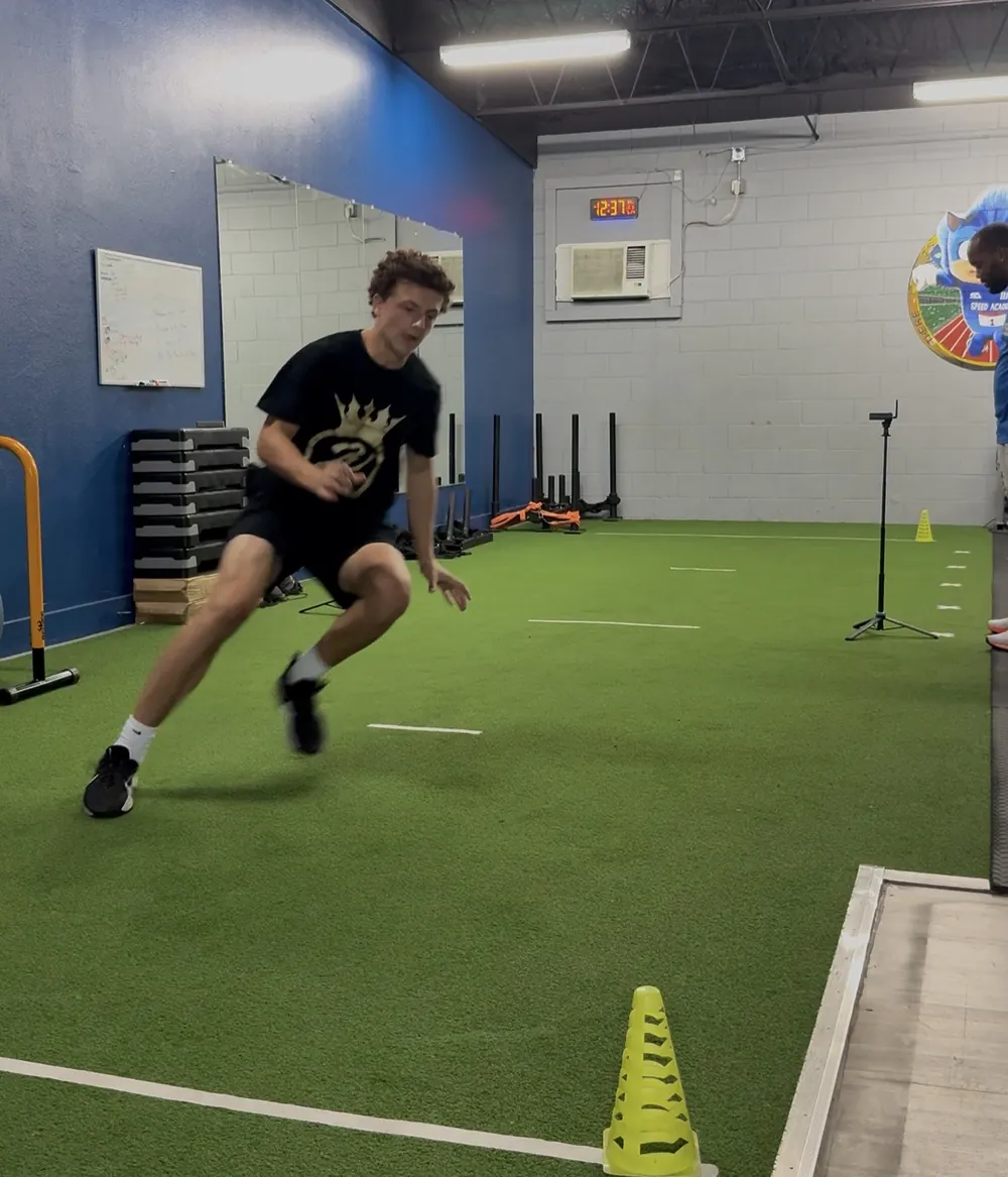 Athlete cutting between cones on the turf during an agility drill
